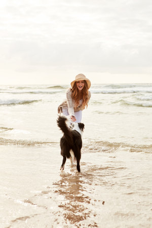 Enjoying a day of play at the beach. a young woman spending some time with her dog at the beach.の写真素材