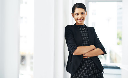 Im confident in what I do. Cropped portrait of an attractive young businesswoman standing with her arms folded in a modern office.の写真素材