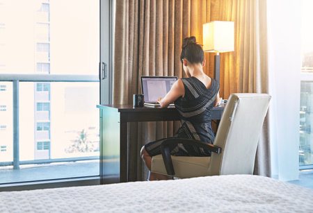 Booked in for business. a young businesswoman working in her hotel room.の写真素材