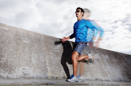 Running on adrenaline. Action shot of a sporty young man running outdoors.の写真素材