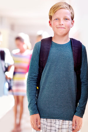 Getting the best education...Portrait of a young boy standing in a school hall.