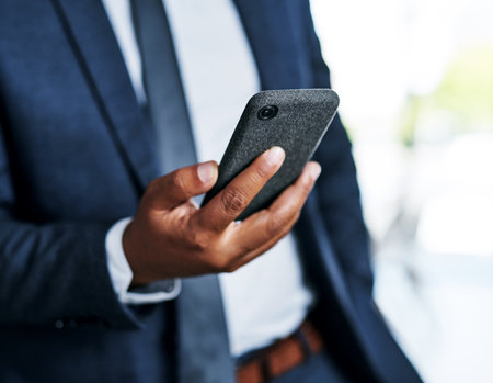 Time to make that major phonecall. an unrecognizable businessman using a smartphone while standing in a modern office.の写真素材
