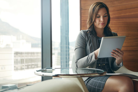 Digitizing her work tasks. a young businesswoman sitting in her office and working on her tablet.の写真素材