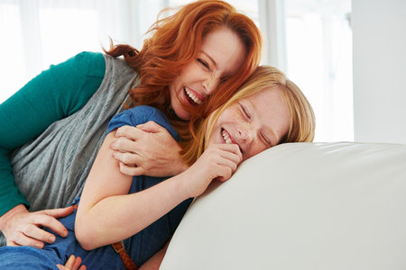 So much love. a mother and young daughter sitting on the sofa at home.の写真素材