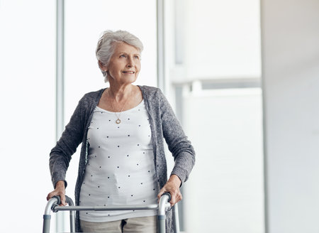 My walker helps me to get around. a senior woman walking with the assistance of a walker.の写真素材