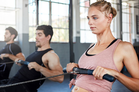 Focused on fitness. a group of people working out on rowing machines in a gym.