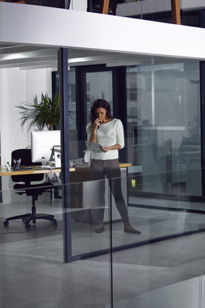 She knows her hard work will pay off. a focussed businesswoman working late in her office.の写真素材