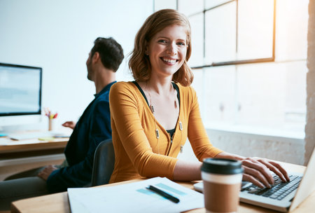 Ill create my own success. Cropped portrait of an attractive young businesswoman working on her laptop in a modern office.の写真素材