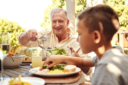 Laid back Sunday lunch with the family. a family eating lunch together outdoors.の写真素材