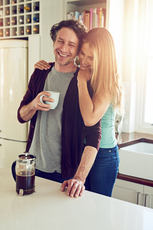 Coffee is a hug in a mug. an affectionate couple in the kitchen.の写真素材