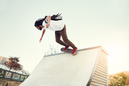 Hes gunning for the top spot. Full length shot of a young man doing tricks on his skateboard at a skate park.の写真素材