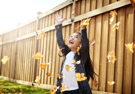 And the leaves came tumbling down. an adorable little girl enjoying an autumn day outdoors.の写真素材
