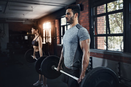 Turn intentions into actions. a young man and woman working out with weights at the gym.