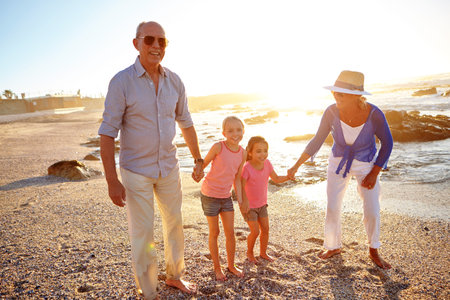 Walks on the beach are worth a thousand words. a grandparents enjoying a day at the beach with their...
