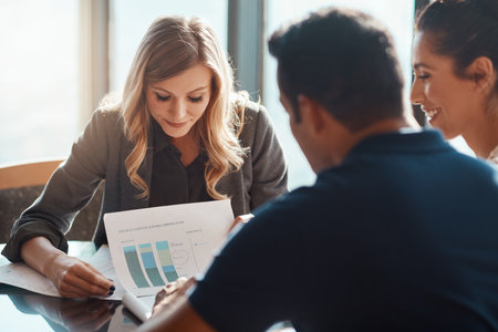 Putting figures into focus. a young couple meeting with a financial planner in a modern office.の写真素材