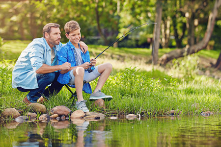 So now its a just a matter of patience. a father teching his son how to fish out in the woods.の写真素材