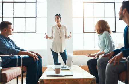 Her ideas are going to change the face of business. a group of young businesspeople having a meeting in a modern office.の写真素材