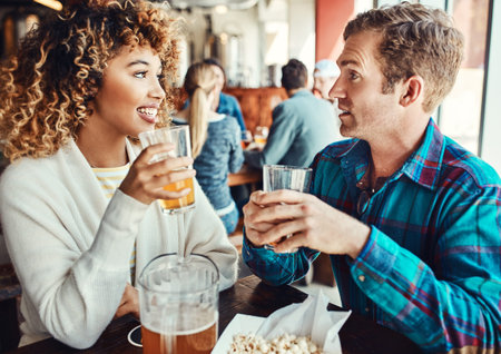 Get to know each other over a cold one. a young couple having drinks in a bar with people blurred in...