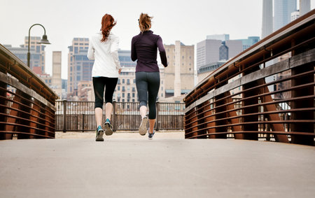 Onward, together. Rearview shot of two unrecognizable young women running through the city.の写真素材