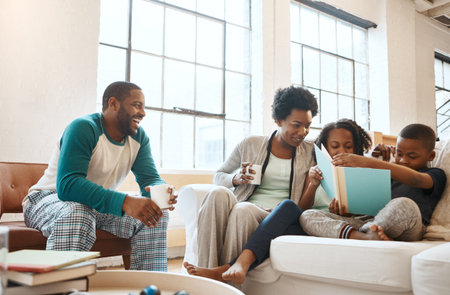 They all love reading. a little brother and sister reading a book while their parents watch at home.