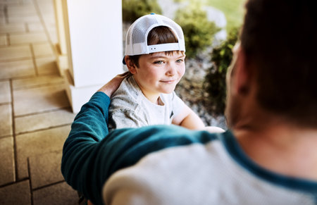 Having a little heart-to-heart. Rearview shot of a father and his son bonding on their porch at home.の写真素材