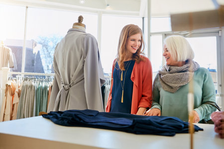 Why not treat your mom to some shopping. a mother and daughter shopping in a clothing boutique.の写真素材