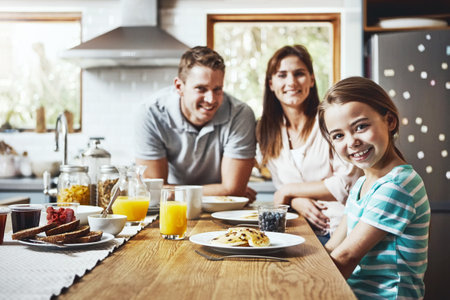 The best start to the day is together. Portrait of a little girl having breakfast with her parents at home.の写真素材