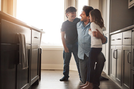 Daddy and his darlings. a happy father bonding with his two young children in the kitchen at home.の写真素材