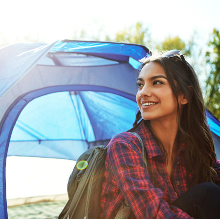 Shes getting away from everything. an attractive young woman sitting at her campsite.の写真素材