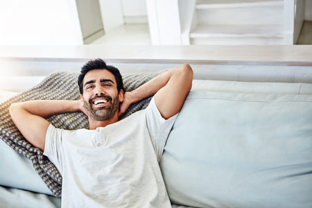 Oh yes, its going to be a good day. a man relaxing on the sofa at home.の写真素材