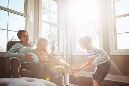 Soon the baby will be adding to the fun. a pregnant woman spending time with her children at home.の写真素材