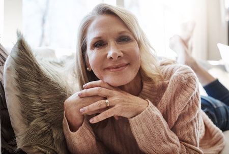 Im on my time now. an attractive mature woman relaxing on the sofa at home.