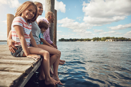 Family outings are her favourite. a young family on a pier while out by the lake.の写真素材