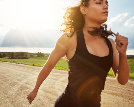 Walking proud. a fit young woman out for a run on a beautiful day.の写真素材