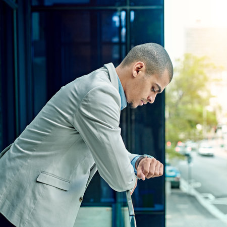 Theres no time like the present. a young businessman checking the time on his watch at work.の写真素材