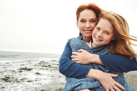 Shes my mother and my best friend. a mature woman embracing her young daughter at the waterfront.の写真素材