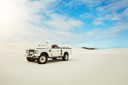 Built to take you deep into the desert. a heavy duty 4x4 parked on some sand dunes.