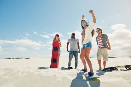 Finding her balance on the board. a group of young friends sandboarding in the desert.