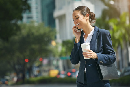 Managing her work commitments on the move. a young businesswoman talking on her phone while out in the city.の写真素材