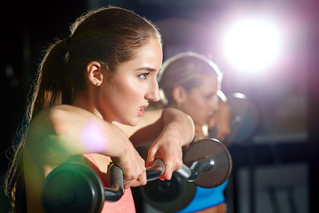 Fit and fierce. two young women working out with weights at the gym.