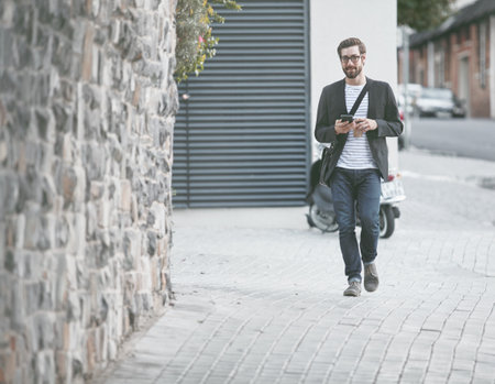 Exploring the city on foot. a stylish young man using a cellphone while out in the city.の写真素材