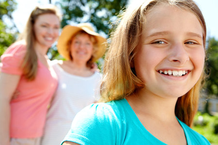 She loves being outdoors. A cute young girl giving you a wide smile while her mother and granny...