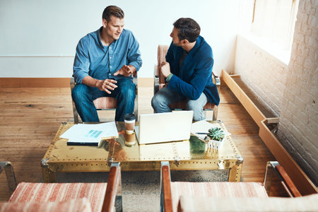 Putting their business on the online map. two young businessmen having a discussion and using a...
