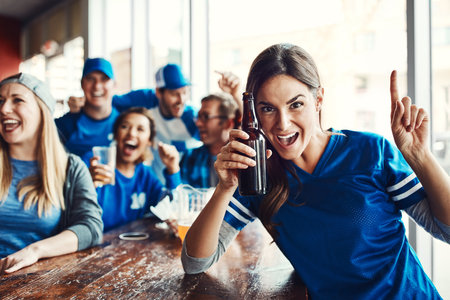 We were going for gold and we got it. Portrait of a woman holding up one finger while watching a sports game with friends at a bar.の写真素材