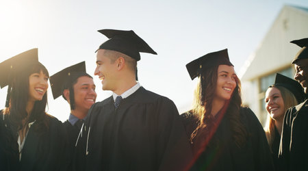We have come a long way guys. a group of cheerful young students standing together on graduation day outside during the day.の写真素材