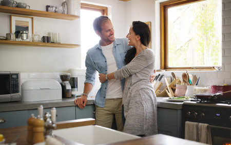 Nothing like sharing your space with your lover. an affectionate young couple embracing each other while standing in their kitchen at home.の写真素材