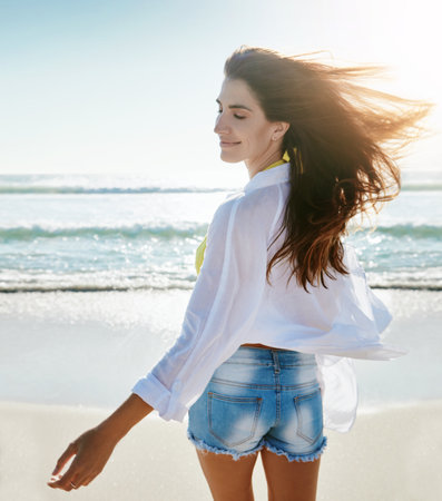 I love everything about the beach. a beautiful young woman enjoying her day at the beach.の写真素材