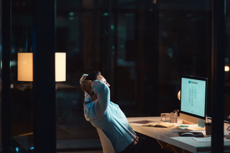 It was hard work but it was worth it. a mature businessman relaxing at his desk during a late night at work.の写真素材