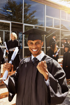 Here I come life. Portrait of a smiling university student holding his diploma outside on graduation...