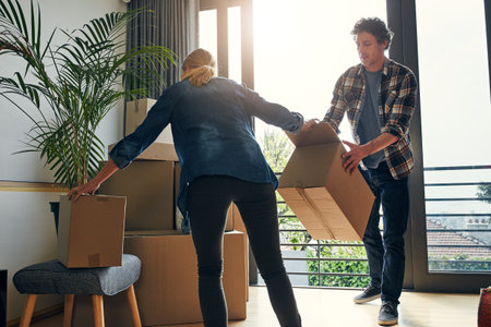 Thanks for helping dear. a focused middle aged couple packing out a boxes at their new home inside during the day.の写真素材